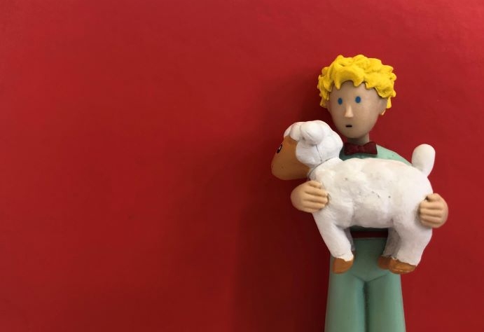 Fotografia de um boneco com uma ovelha ao colo.