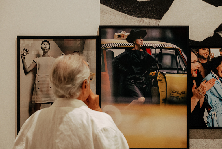 Imagem com um senhor de costas a observar peças da exposição.