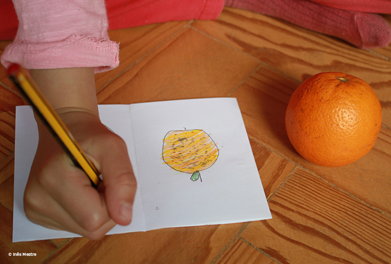 Imagem com uma fotografia de uma mão de criança a desenhar.
