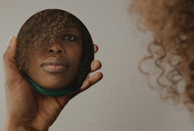 Imagem de uma mulher negra refletida num espelho.