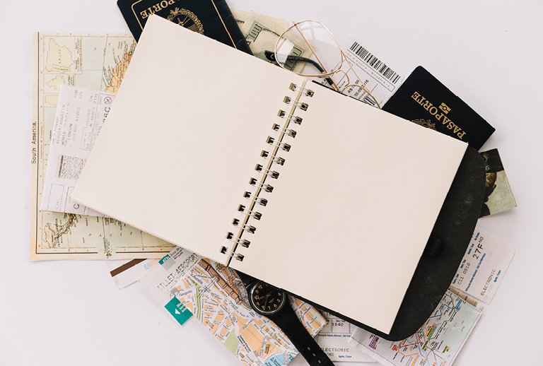 Imagem com caderno em branco e vários folhetos.